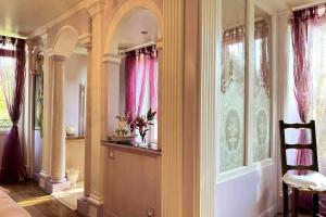 un couloir d'une maison avec des rideaux roses et une chaise dans l'établissement Domaine Le Petit Coubert, à Coubert