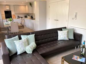a living room with a brown couch and a kitchen at 4 The Bayhouse in Shanklin