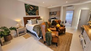 a bedroom with a bed and a couch and a chair at Vredenburg Manor House in Somerset West