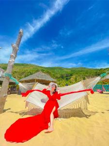 Una mujer con un vestido rojo en una playa en Khách Sạn Nhơn Lý LYS HOTEL, en Quy Nhon