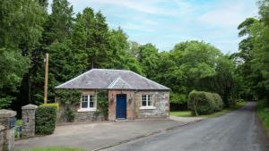 a stone house with a blue door on a road at East Lodge at Ashiestiel in Clovenfords
