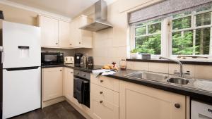 a kitchen with white cabinets and a sink at East Lodge at Ashiestiel in Clovenfords