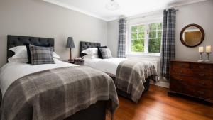 a bedroom with two beds and a mirror and a window at East Lodge at Ashiestiel in Clovenfords