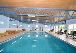 a large swimming pool in a building with chairs at Gone To The Beach - Fishcombe Cove in Brixham