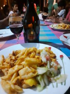 a plate of food with french fries and a bottle of wine at Guest House Basilea in Beruwala