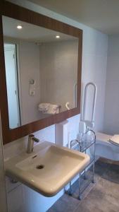 ein Badezimmer mit einem Waschbecken, einem Spiegel und einem Stuhl in der Unterkunft Hotel Campanile Besançon Nord Ecole Valentin in Besançon
