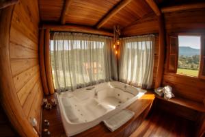 a large bath tub in a room with a window at Hospedaria Refugio do Invernador in Urubici