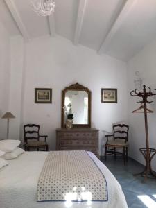 a bedroom with a bed and a mirror and chairs at La Bergerie Pradel in Le Beaucet