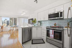 uma cozinha com electrodomésticos de aço inoxidável e uma sala de estar em Modern 2-Bedroom Condo w Floor to Ceiling Windows em Toronto