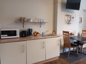 cocina con armarios blancos, fregadero y mesa en Mulberry Lodge, en Blarney