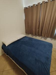 a bed in a room with a blue blanket at Pousada Indi in Ribeirão Preto