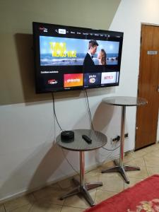uma televisão de ecrã plano numa parede com uma mesa e uma mesa; em Pousada Indi em Ribeirão Preto