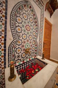 a mosaic tile wall with a tub filled with flowers at Dar houda in Fès