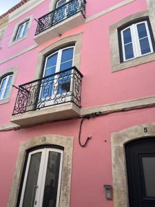 een roze gebouw met ramen en een balkon bij PÉROLA DO BOCAGE - no coração de Setúbal in Setúbal
