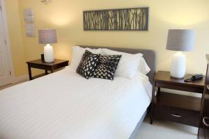 a bedroom with a white bed with two tables and two lamps at Deluxe Downtown Apt #404 with AC in Halifax