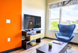 an orange living room with a blue chair and a television at Private Downtown Apartment With City View in Raleigh