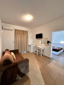 een woonkamer met een bank en een bureau met een televisie bij OMIROS HOTEL in Mesariá
