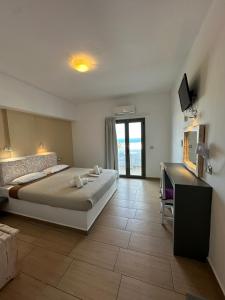 sypialnia z dużym łóżkiem i telewizorem w obiekcie OMIROS HOTEL w mieście Mesaria