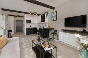 uma sala de estar com um sofá e uma cozinha com uma televisão em Modern Studio Wróblewskiego with Balcony and Free Parking by Renters em Łódź