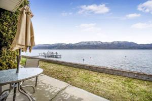 a table with an umbrella next to a body of water at The Lakeside Cabin with wide outside space #105 in West Kelowna