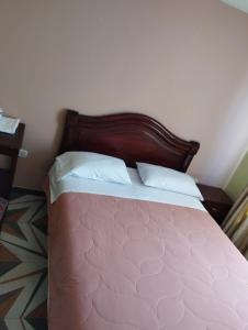 1 dormitorio con cama rosa y cabecero de madera en Hotel Torre Bolívar, en Pasto