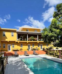 an exterior view of a yellow building with a swimming pool at Tropical Apartments Tobago in Scarborough