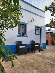 ein blau-weißes Gebäude mit Stühlen und einem Fenster in der Unterkunft Monte da Caldeirinha in Luz de Tavira