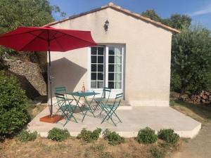 a table and chairs with a red umbrella on a patio at Nîmes calme in Nîmes