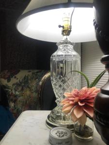 a glass lamp sitting on a table with a flower at The Nauvoo Grand Bed & Breakfast in Nauvoo