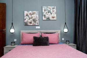 a bedroom with a pink bed with three paintings on the wall at Ocean Pearl in Kos