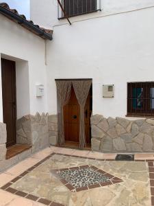 a building with a wooden door and a stone wall at El callejón in Benarrabá