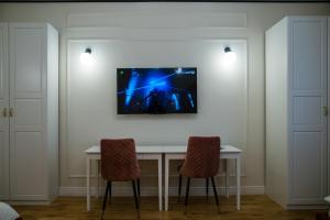 a table with two chairs and a tv on a wall at Apartament Wspomnień in Zamość