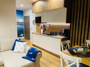 a kitchen and a living room with a couch and a table at Sunset Resort Apartament Marco Marina in Grzybowo
