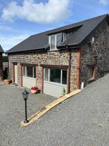 a brick house with a driveway in front of it at Countryside cottage with private garden & hot tub in Lifton