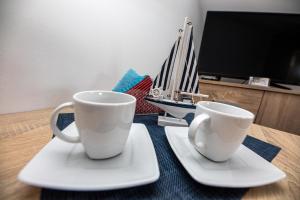 two white cups sitting on plates on a table at Dom Wypoczynkowy Anna in Kołobrzeg