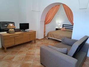 a bedroom with a bed and a couch and a tv at Marosi in Pantelleria