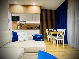 a living room with a couch and a table with chairs at Sunset Resort Apartament Marco Marina in Grzybowo