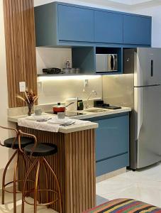 a kitchen with blue cabinets and a stainless steel refrigerator at Flat Encantador Allianz Park 708 in Sao Paulo