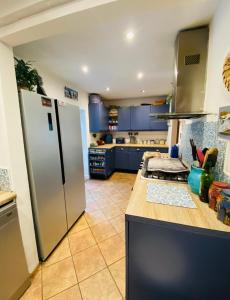 a kitchen with blue cabinets and a stainless steel refrigerator at Peak District Home from Home! in Grindleford Bridge