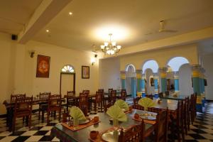 a dining hall with tables and chairs and a chandelier at THE CHETTINAD HERITAGE in Kānādukāttān