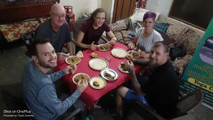 un grupo de personas sentadas alrededor de una mesa comiendo comida en Khajuraho Homestay en Khajurāho