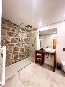 bagno con parete in pietra, lavandino e doccia di Paços do Douro, Chambre privée avec piscine a Romariz