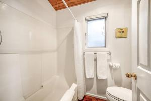 a white bathroom with a toilet and a window at Beautiful Cabin Right next to Lake Okanagan #5 in West Kelowna