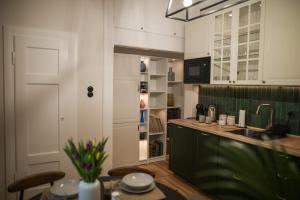 a kitchen with green cabinets and a table and a sink at Apartament Wspomnień in Zamość