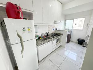 uma cozinha com armários brancos e um frigorífico branco em 207- APARTAMENTO de 2 QUARTOS no ALTO CAIÇARAS em Patos de Minas