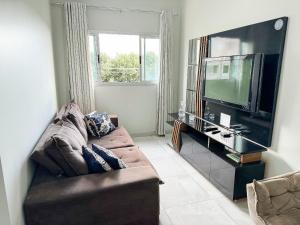 uma sala de estar com um sofá e uma televisão de ecrã plano em 207- APARTAMENTO de 2 QUARTOS no ALTO CAIÇARAS em Patos de Minas