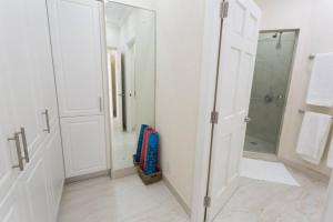 Baño blanco con ducha a ras de suelo y espejo en 102 Lighthouse Bay Barbados, en Christ Church
