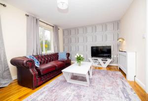 a living room with a leather couch and a tv at Charming 4-bedroom home in Corby in Great Oakley