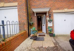uma casa de tijolos com duas portas brancas e vasos de plantas em Charming 4-bedroom home in Corby em Great Oakley