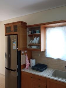 a kitchen with a refrigerator and a sink and a window at Glaros in Ermioni